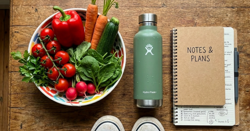 Bowl of fresh vegetables, green water bottle, and 2024 planner on wooden table